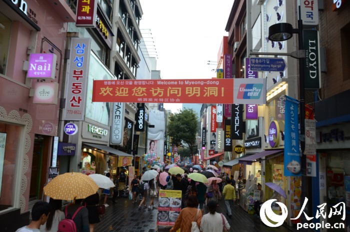 國慶黃金周期間，冒雨在明洞街頭購物的中國游客們。（攝影：裴埈基）