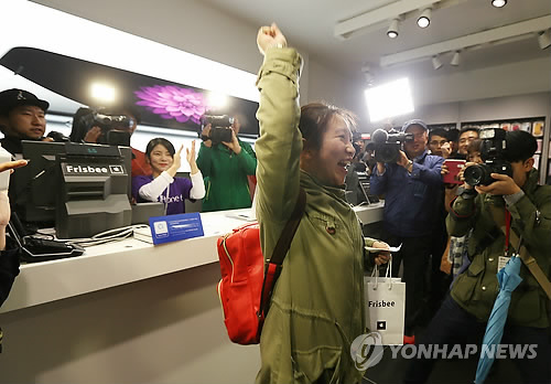 圖為位于首爾明洞的蘋果專賣店Frisbee第一個買到iPhone6的顧客在拿到手機后舉手歡呼。