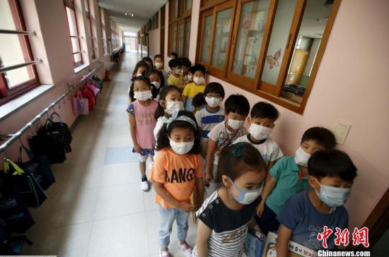 資料圖：韓國未停課的學校，學生課前戴口罩測體溫。