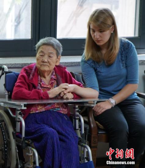 一名昔日被日軍強征的“慰安婦”在接受采訪過程中一直握緊著身旁外國志愿者的手。 中新社發 吳旭 攝