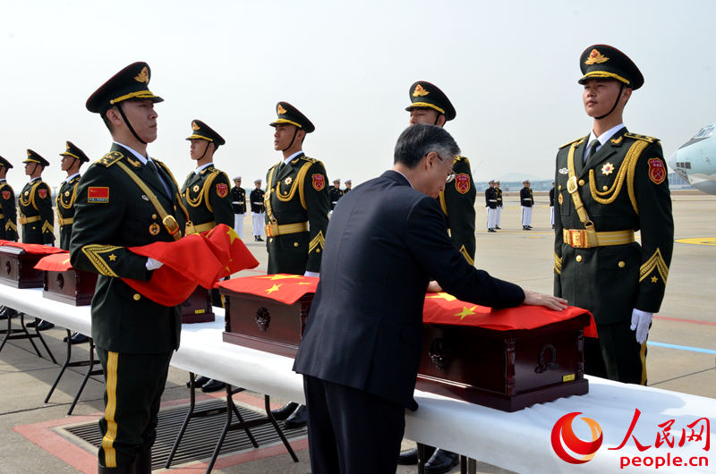 中國駐韓國大使邱國洪為中國人民志愿軍烈士遺骸棺槨覆蓋國旗。夏雪 攝