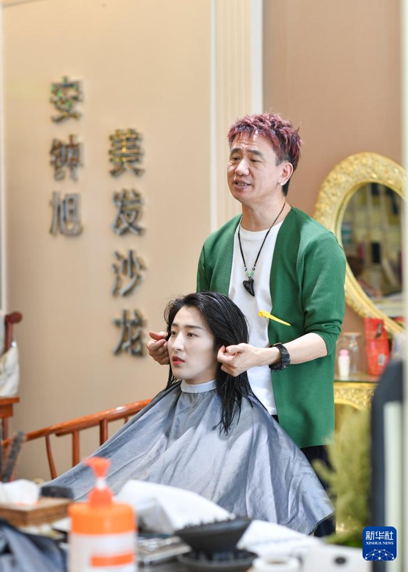 在位于烏魯木齊市城區的美發店，安鐘旭和一名顧客交流，了解她的美發需求（3月15日攝）。