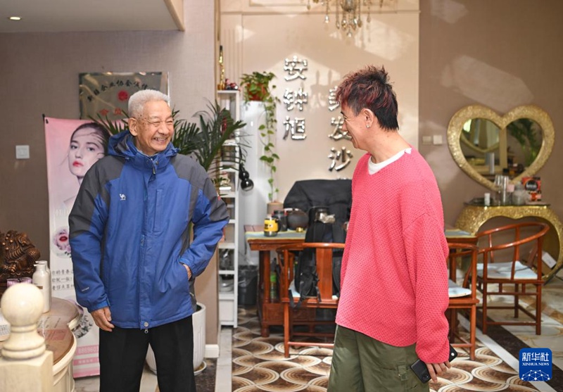 在位于烏魯木齊市城區的美發店，一名老人在免費理發后，向安鐘旭（右）道別致謝（3月17日攝）。