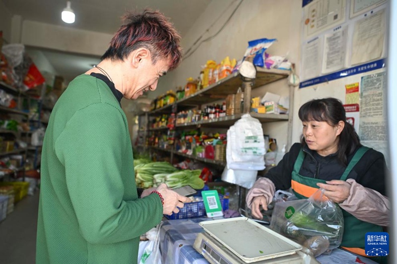 安鐘旭（左）在烏魯木齊南郊的一家商店買菜（3月18日攝）。