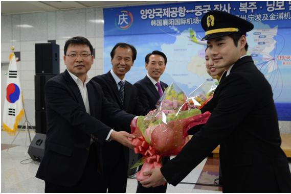 12月4日在襄陽國際機場舉行的真航空襄陽-長沙開航儀式上，江原道知事崔文洵（左中）、真航空總經理馬元（左一）、韓國航空公司總經理金碩基和真航空乘務員一起拍照留念。
