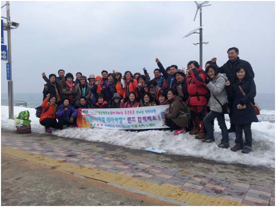 旅游團隊抵達正東津站后在冬季美麗的大海邊合影留念。