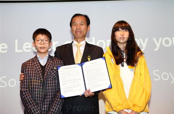 學生們在2014年4月28日召開的2018年平昌冬奧會賽場建設促進情況新聞發布會上朗讀信件，祝愿冬奧會成功舉辦。江原道知事崔文洵與學生們合影留念。